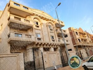 واجهة مبنى عصرية من حجر هاشمي رأس أبيض مائل للخضرة، تظهر تفاصيل النحت والأبعاد.