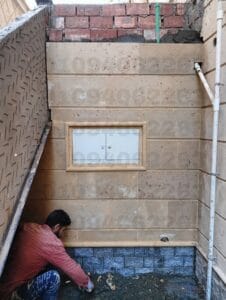 واجهة مبنى عصرية من حجر هاشمي رأس أبيض مائل للخضرة، تظهر تفاصيل النحت والأبعاد.